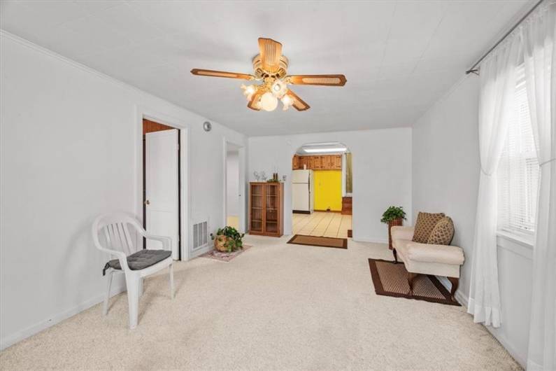 Alternate view of 2nd floor apartment living room, looking into the kitchen. The 2nd door on the left leads to a bonus room. There is hardwood flooring under this carpet.