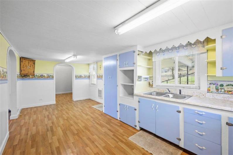 Alternate view of the kitchen from the stove area looking toward one of the bedrooms ahead. New vinyl flooring has just been installed.