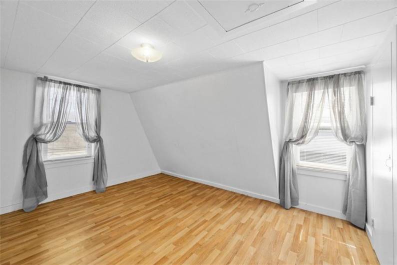 The bedroom off of the living room of the small house is 12'x8'. It features 2 windows. New vinyl flooring has just been installed.