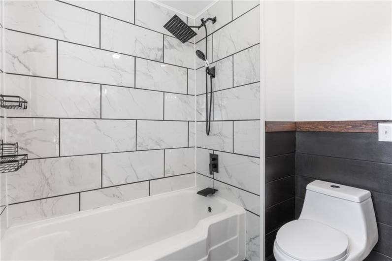 A gorgeous tile tub surround and black fixtures bring this bathroom an air of modernity.