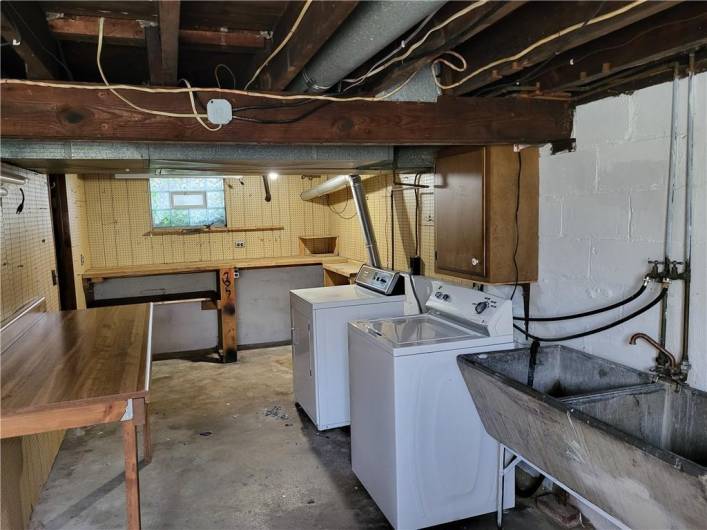 Laundry area has a table to fold clothes & a work bench is in the background