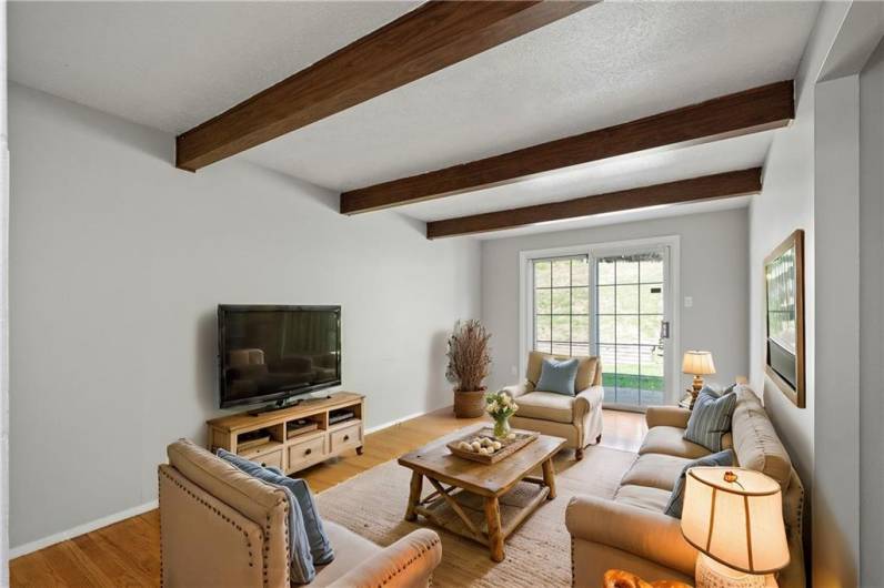 A cozy Family Room with wood beams and sliding glass doors lead out to the patio and back yard. Virtually staged photo to illustrate what is possible!