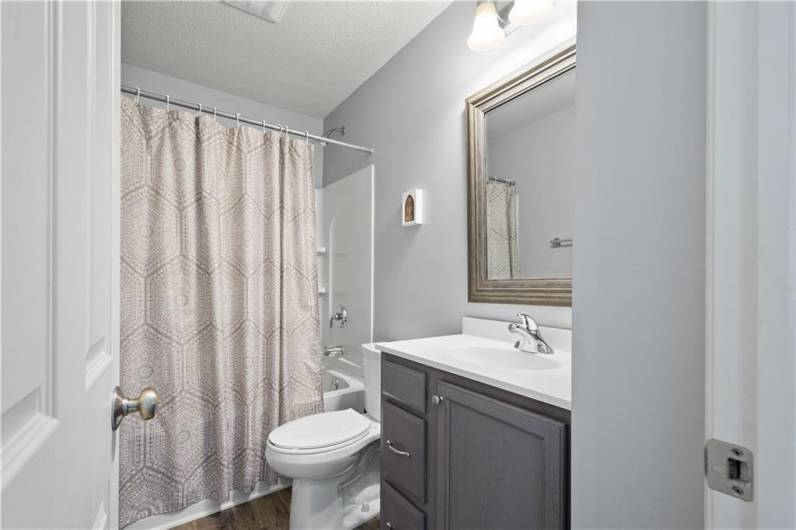 Hallway bathroom with modern flooring and fixtures.