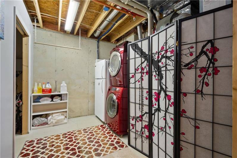 High ceilings in the generously sized laundry room. An additional storage room is located behind the door to the left.