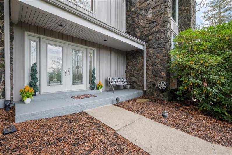 Step onto the spacious covered porch, surrounded by mature landscaping that enhances the home’s charm and curb appeal. The wide steps lead to a beautiful double-door entry, adorned with leaded glass and sidelights, creating a warm and inviting welcome.