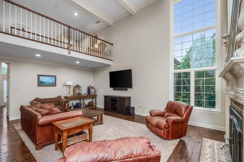 Two story Great Room with grand fireplace and an abundance of natural light from all of windows overlooking with pool.