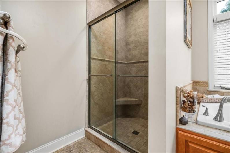 Floor to ceiling tiled shower with glass door enclosure.