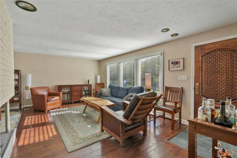 A view of the custom front door and entrance into the beautiful living room area with newer engineered hardwood flooring.