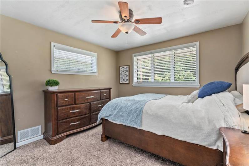 Master bedroom with ceiling fan and overhead lighting. Windows positioned perfectly for easy furniture placement.