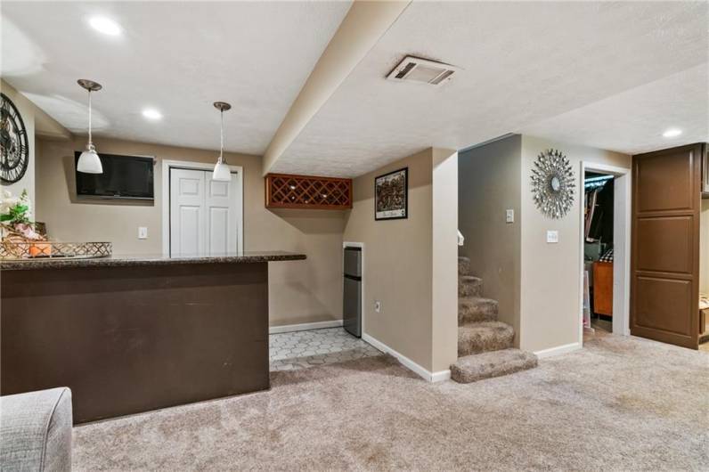 Bar area in game room with mini refrigerator, wine rack and tv included.  Door behind bar is great storage closet.