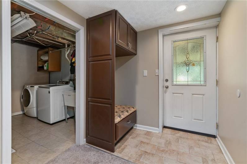 Steel insulated door in game room walks out to concrete patio and has coat rack and bench seat that creates a little mud room.