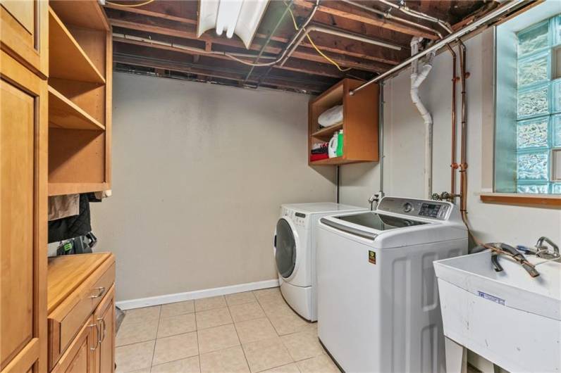 Large laundry room with shelving and cabinets with pull outs.  Includes Kenmore washer, dryer and utility sink.