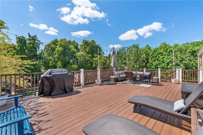 Oversized deck with vinyl easy to maintain railing and steps that lead to backyard.