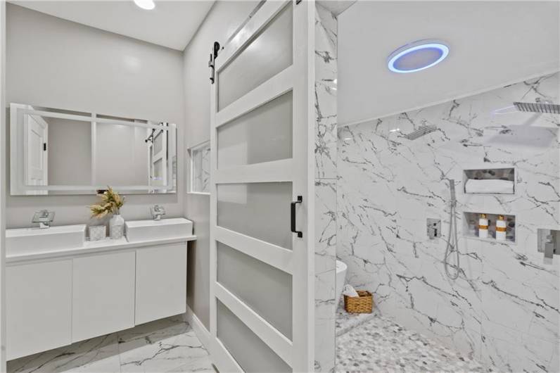 This spacious bathroom features elegant marble finishes and ample storage space.