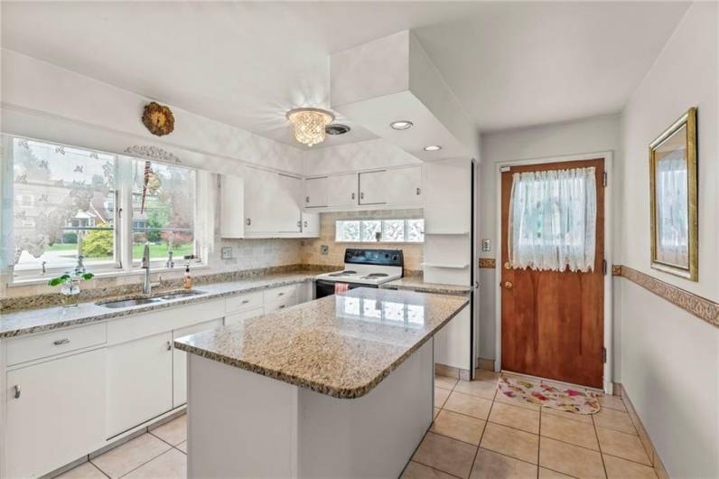 Glass Block Windows on each side of Kitchen, Elegant Crystal Light Fixture, Granite Counter Tops, Lots of Cabinetry, Breakfast Bar Island and Door to Side Driveway