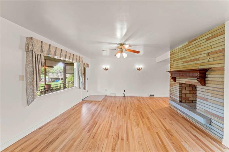 View of Stunning Stone Fireplace in Living Room, Ceiling Fan Light, Gorgeous Refinished Hardwood Floors & Wall Light Sconces