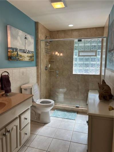 Lovely newer ceramic tiled bathroom on first floor with oversized shower and glass block for privacey