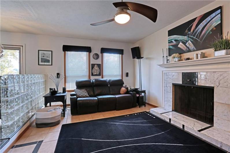 Enjoy the wood-burning fireplace with marble surround in the family room. The family room is partially divided from the kitchen with this unique glass block wall. The speakers and surround sound are included.