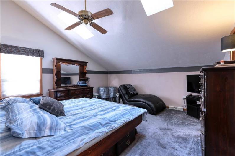 The primary bedroom features a vaulted ceiling with two skylights, an ensuite bath, and a walk-in closet.