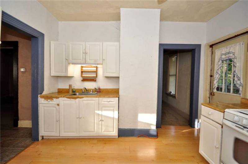 Another view of the kitchen with the entryway to the left and access to the back deck to the right and dining room straight ahead