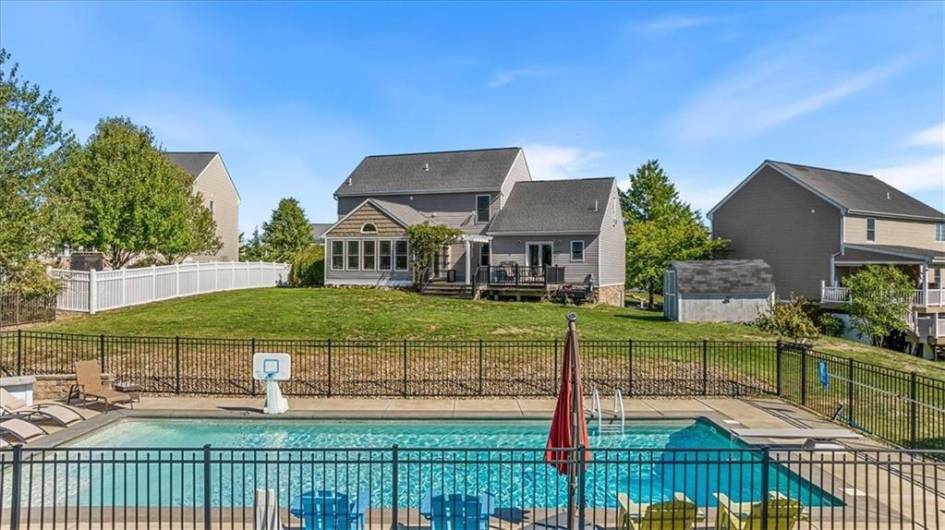 The back of the house offers a deck with seating, a large yard, and beautiful pool