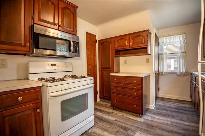 Kitchen, newer flooring, wood cabinetry, gas stove and microwave.  Coffee bar area