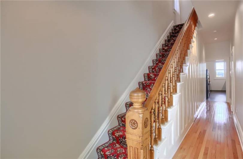 The main hallway on the first level of the home leads to the kitchen and to multiple rooms to the right.