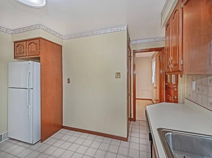 Area next to the refrigerator is cozy spot for a table for quick meals or morning coffee. The open doorway leads into a bedroom. The basement door is to the left behind the wall the refrigerator is on.