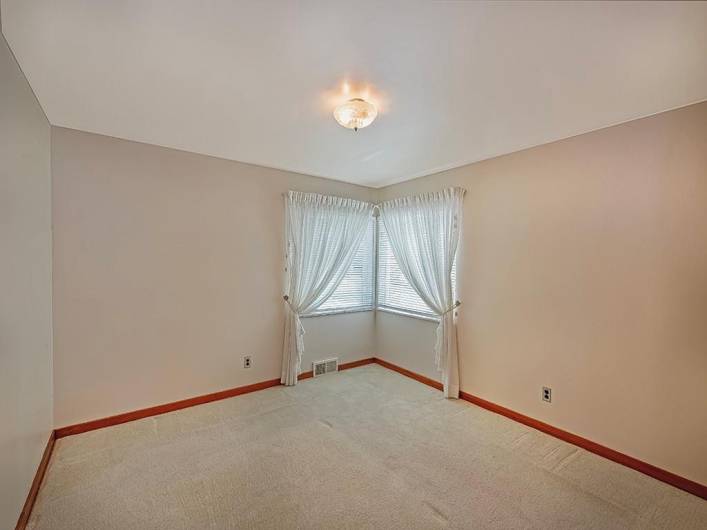 View of primary bedroom without it virtually staged. Hardwood floors under the carpet in all the bedrooms.