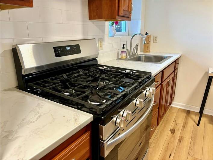 New gas stove, countertops, backsplash and flooring.