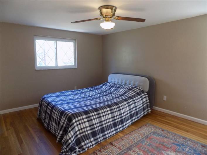 Master bedroom features gleaming hardwood floors and ceiling fan.