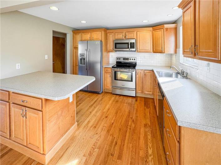 Updated kitchen with stainless steel appliances, tile backsplash, and recessed lighting.