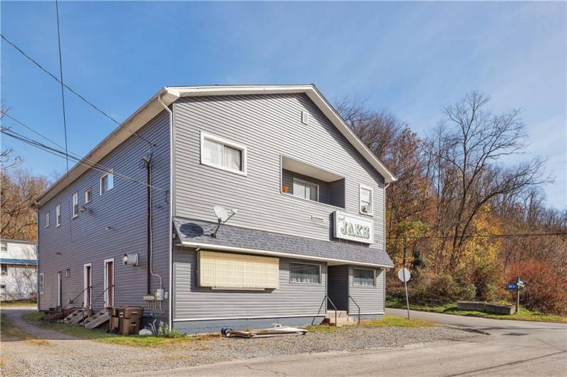 Driveway to 6 parking spaces in rear, and side entries to bar and 3 upper level apartments.