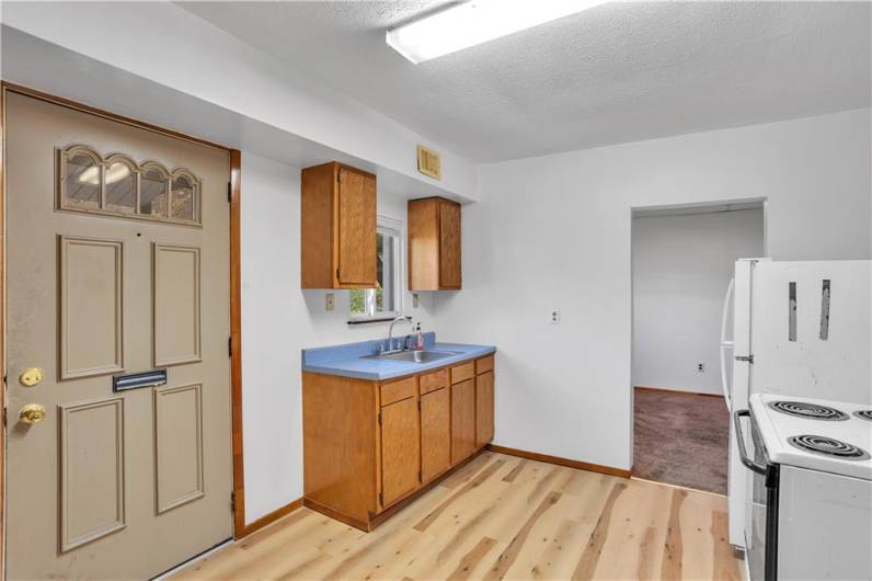 Kitchen and entry to Apartment #1 with new wood-look floor and fresh paint. Entry from rear parking area.