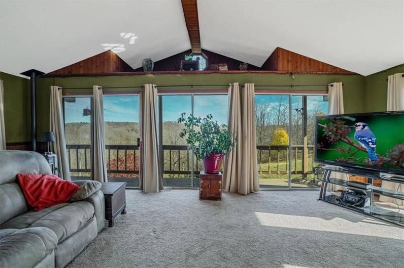 Bright and airy sunroom with vaulted ceilings, large sliding doors, and panoramic views of the outdoors. Ideal space for relaxing and enjoying natural light year-round.