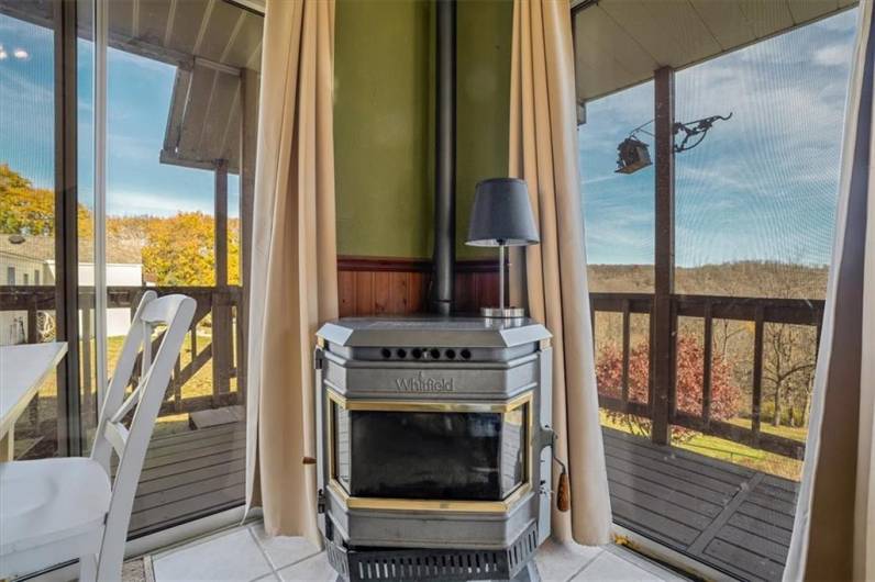 Cozy wood-burning stove in the sunroom with floor-to-ceiling windows, creating a warm ambiance and offering a charming touch for cooler months.