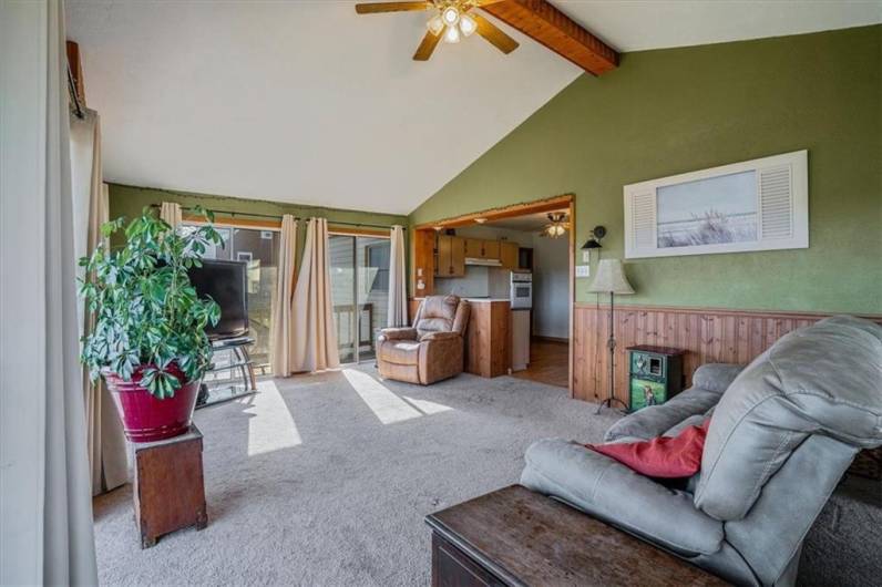 Spacious sunroom with vaulted ceiling, connecting to the kitchen area, perfect for relaxing or entertaining while enjoying natural light and scenic views.