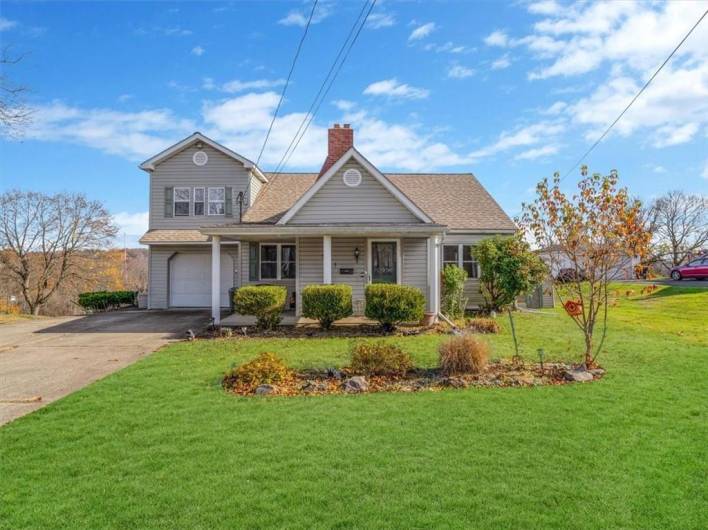 Charming multi-level home with a classic design, featuring a welcoming front porch, mature landscaping, and a one-car garage.