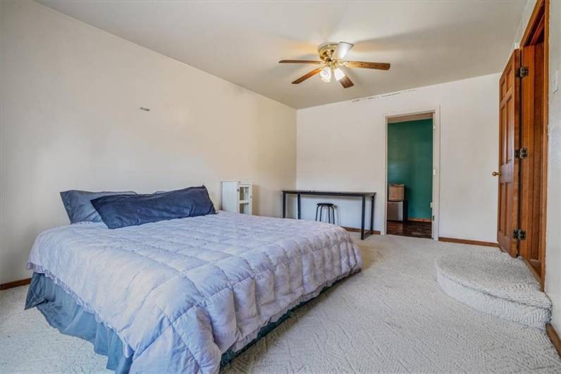 With plush carpeting and space for both a bed and workspace, this bedroom (upstairs) offers versatility for various needs. The natural lighting creates a warm and welcoming atmosphere.