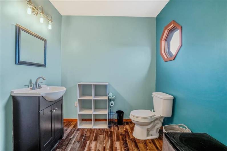 This roomy upstairs bathroom boasts a stylish vanity and a compact storage unit, all set against calming teal walls. The octagonal window adds unique character, making it both functional and charming.