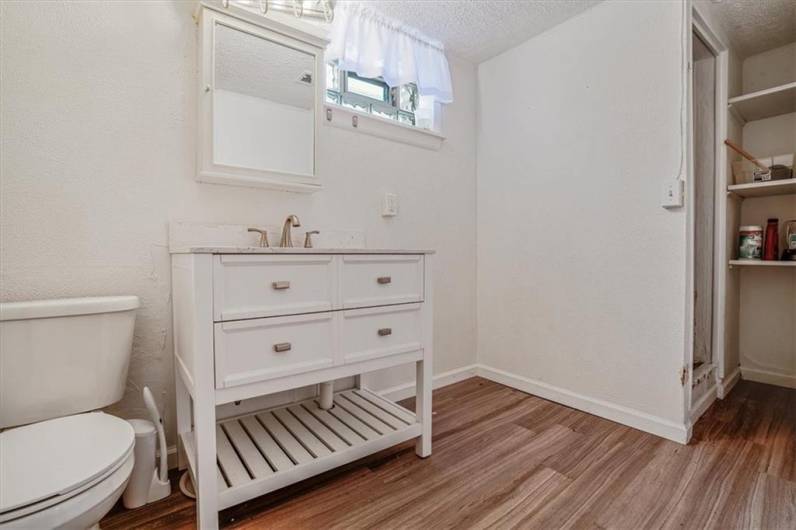 Recently updated bathroom featuring a stylish vanity with ample storage, open shelving, and natural light from a high-set window.