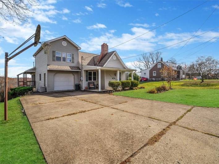 Spacious driveway with ample parking, complemented by a well-maintained front yard and a vintage basketball hoop for added character.