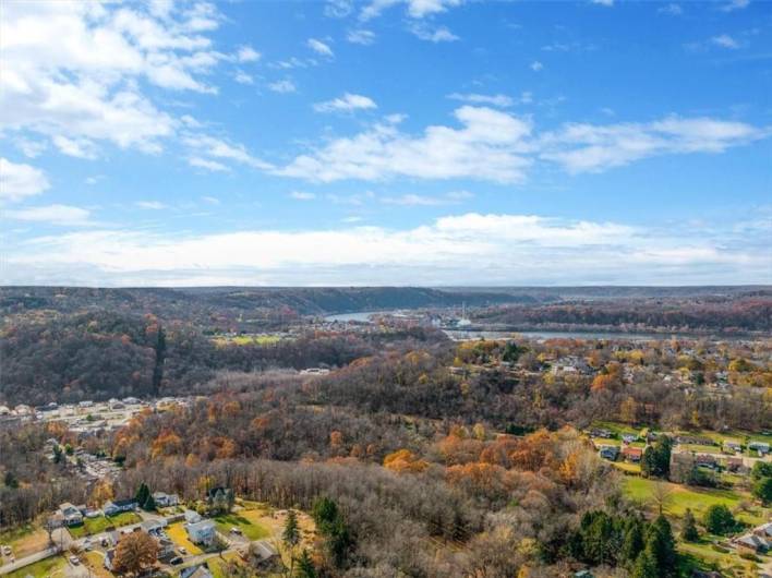 This image goes beyond the immediate neighborhood to showcase a broader valley and possible river in the distance, providing a beautiful backdrop and highlighting the area's proximity to nature.