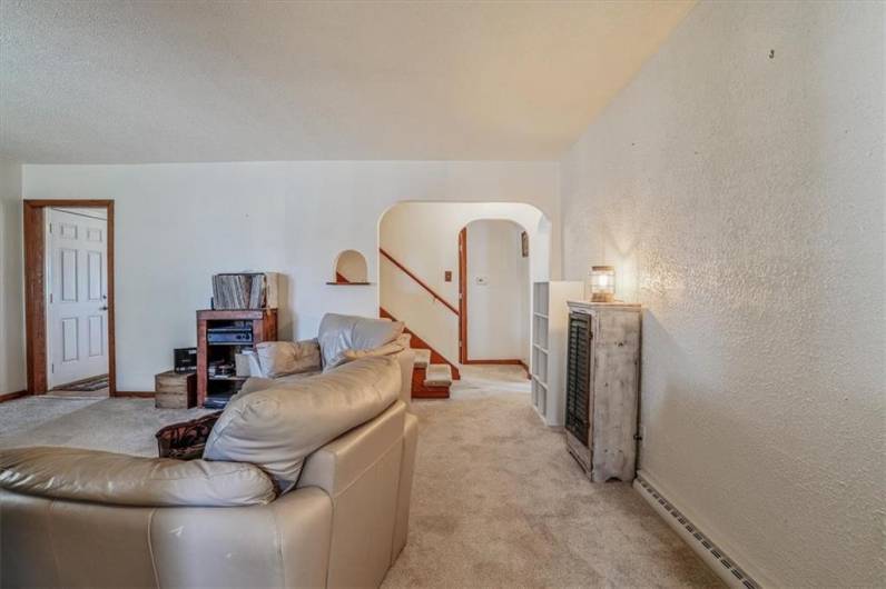 Warm and inviting living room viewed from the entryway, showcasing a stunning stone fireplace, plush carpeting, and large windows that bring in natural light.