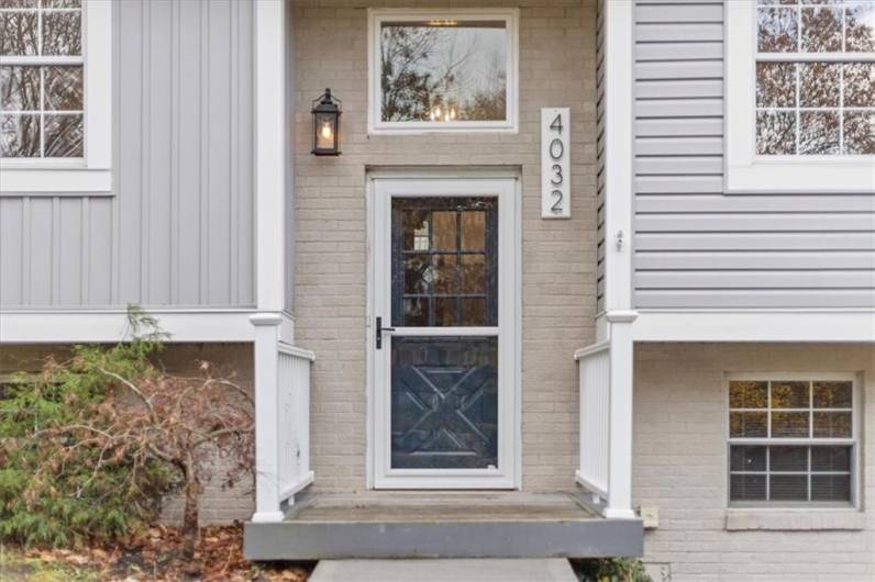 New concrete stairs and walkway lead up to the front door with storm door and retractable half screen