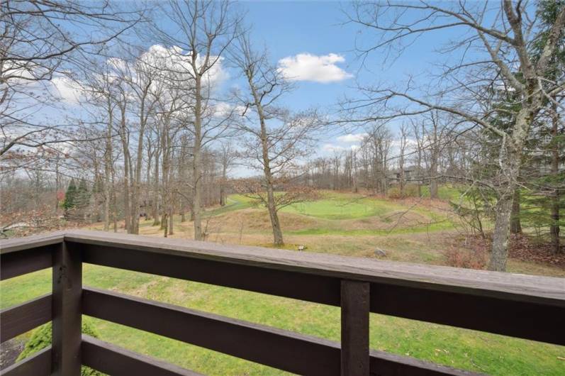 Views of the golf course and wooded property from the primary bedroom balcony.