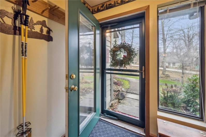 The vestibule features a vertical ski rack, coat hooks, tiled floor, and storm door with sliding glass and screen.