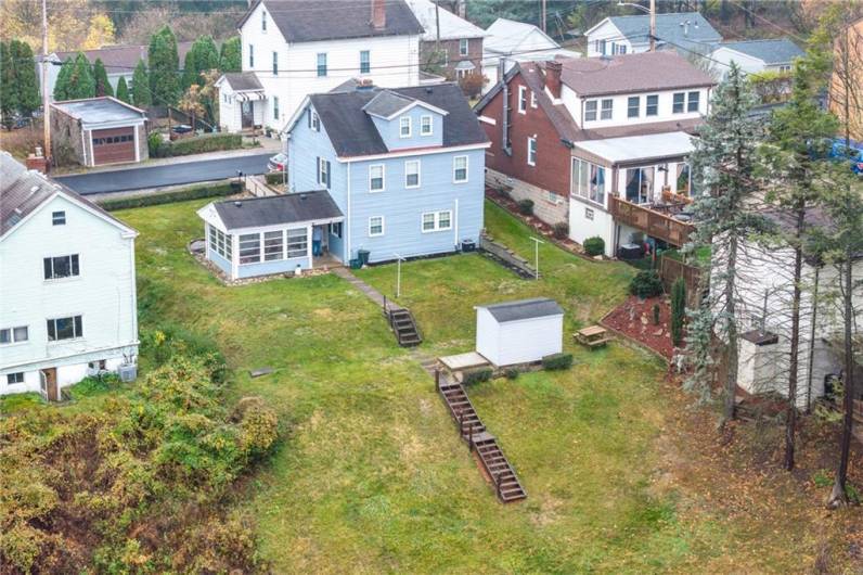 Back of the house with a tiered yard and shed