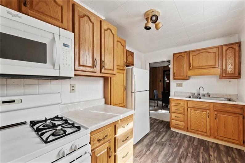 Well maintained kitchen equipped with gas stove, refrigerator, microwave, and pantry.