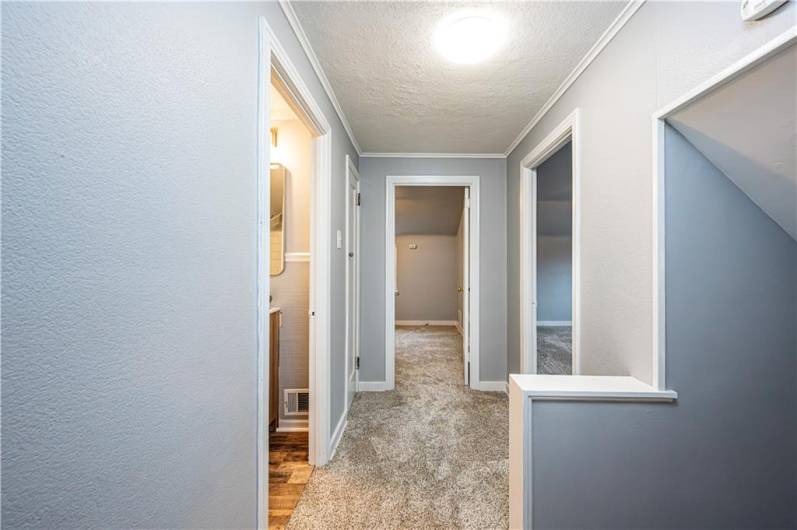 A view of the second level hallway. The steps and upstairs has new carpeting and lights. There is a linen closet.